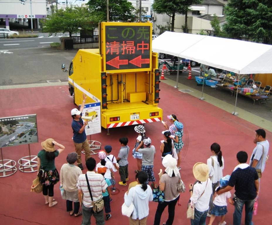 写真：【標識車の説明を受けている参加者たち】