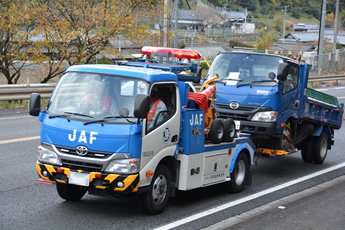 写真：【道路パトロールカーの先導により、ＪＡＦ作業車による放置トラックの移動作業】