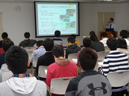 写真：【事務所での説明を熱心に聞く学生】